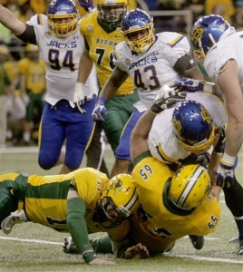 FILE - In this Nov. 1, 2014, file photo, North Dakota State quarterback Carson Wentz, left, and offensive lineman Adam Schueller, middle, bring down South Dakota State  linebacker J.T. Hassell after he intercepted a pass by Wentz during the first half of an NCAA college football game in Fargo, N.D. There is no easing into the conference season for four-time national champion North Dakota State. The Bison open Missouri Valley Football Conference play at South Dakota State, a team that has not only become their fiercest rival, but one that has been impressive in nonconference play. (AP Photo/Bruce Crummy, File)